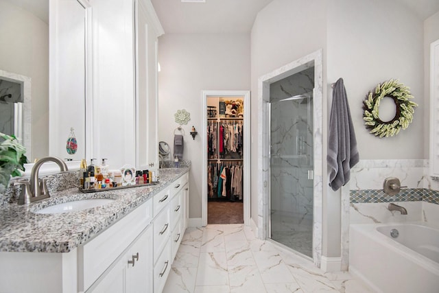 bathroom featuring marble finish floor, a garden tub, a marble finish shower, a spacious closet, and vanity