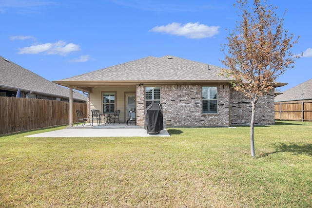 back of house featuring a shingled roof, a fenced backyard, a yard, a patio area, and brick siding