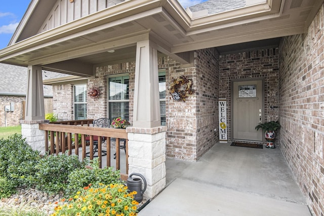 entrance to property featuring covered porch, board and batten siding, and brick siding