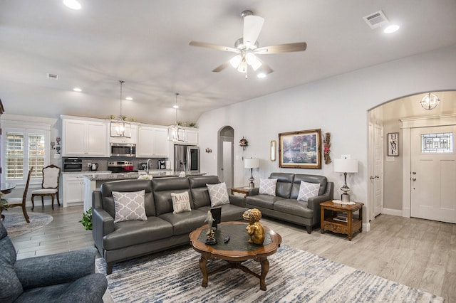 living area featuring light wood-type flooring, visible vents, arched walkways, and recessed lighting