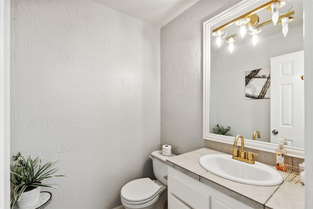 half bath featuring a textured wall, toilet, and vanity