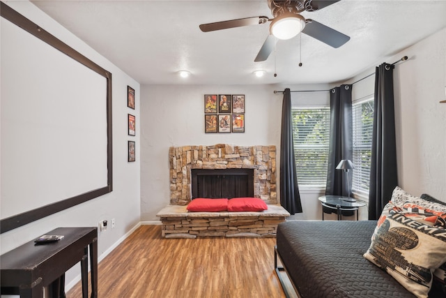 bedroom with baseboards, a fireplace, wood finished floors, and ceiling fan