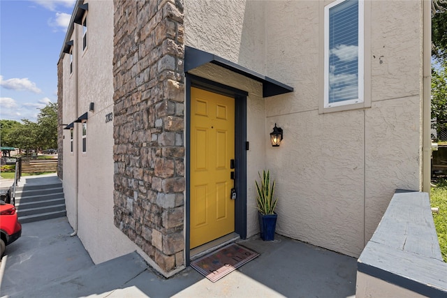 doorway to property featuring stone siding and stucco siding