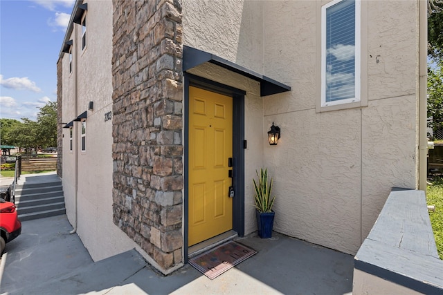 entrance to property with stone siding and stucco siding