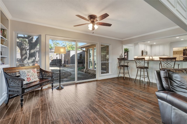 living area with a ceiling fan, crown molding, baseboards, and wood finished floors