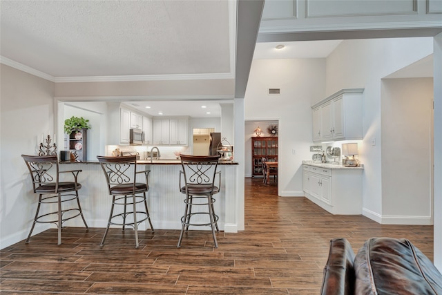 kitchen featuring appliances with stainless steel finishes, visible vents, dark wood finished floors, and a kitchen bar