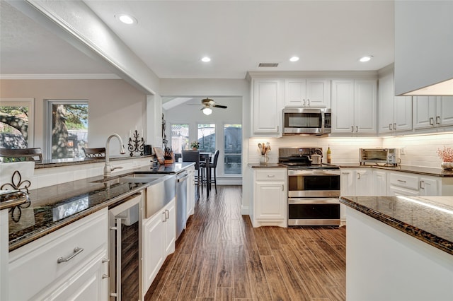 kitchen featuring wine cooler, stainless steel appliances, visible vents, backsplash, and dark stone counters