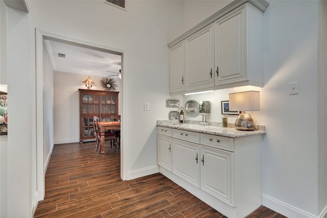 bar with ceiling fan, wood finish floors, visible vents, and baseboards