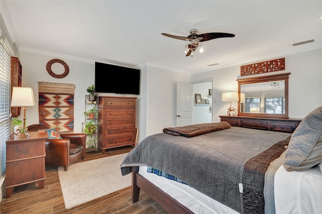 bedroom with ceiling fan, wood finish floors, visible vents, and crown molding