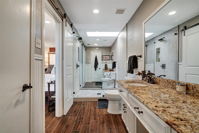 bathroom with vanity, a shower stall, toilet, and wood finished floors