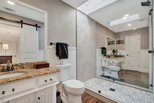 bathroom with a wainscoted wall, visible vents, a tile shower, and toilet