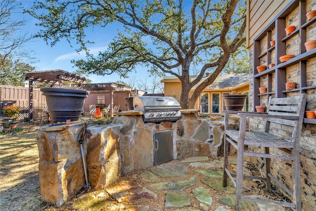 view of patio featuring exterior kitchen, fence, grilling area, and a pergola