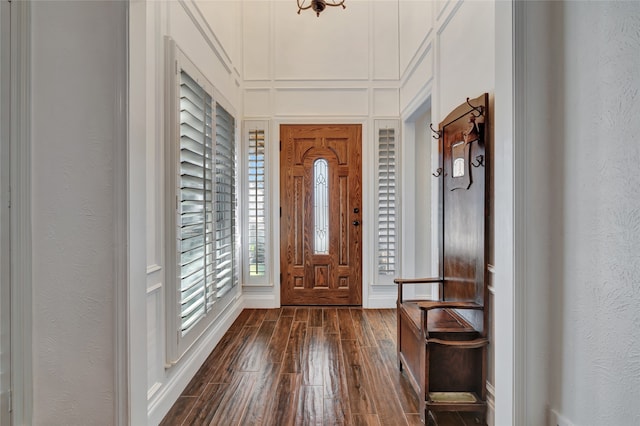 entrance foyer with a textured wall, dark wood-type flooring, and a decorative wall