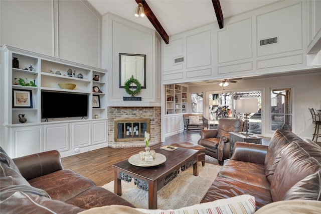 living room with wood finished floors, beamed ceiling, a towering ceiling, and visible vents