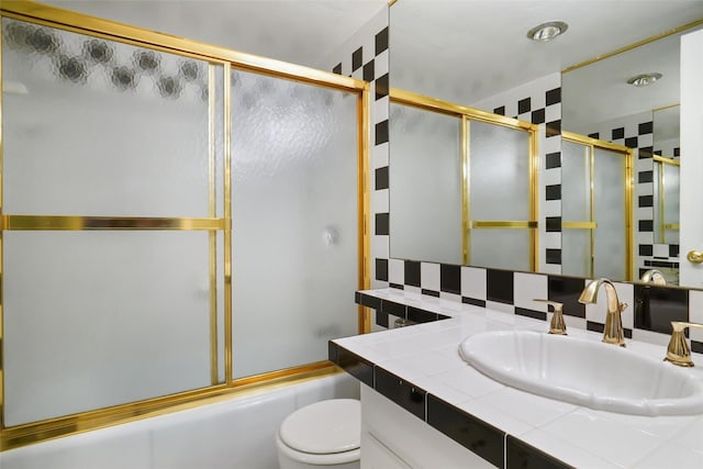 full bathroom with vanity, toilet, tasteful backsplash, and bath / shower combo with glass door