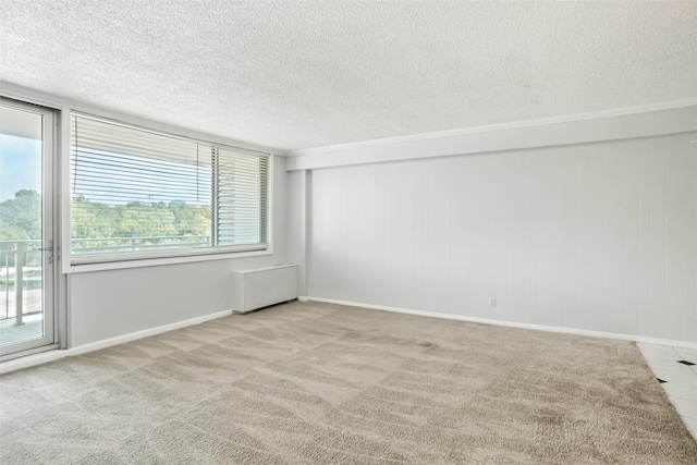 carpeted empty room with radiator, a textured ceiling, and baseboards