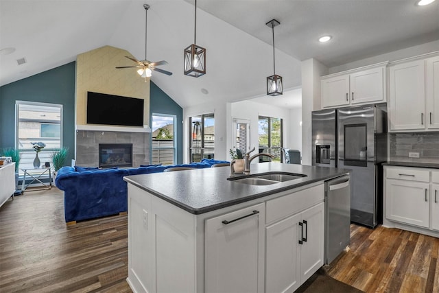 kitchen featuring dark wood-style floors, a fireplace, dark countertops, appliances with stainless steel finishes, and a sink