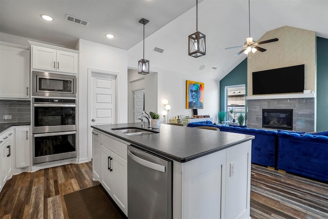 kitchen with dark countertops, visible vents, appliances with stainless steel finishes, and a sink