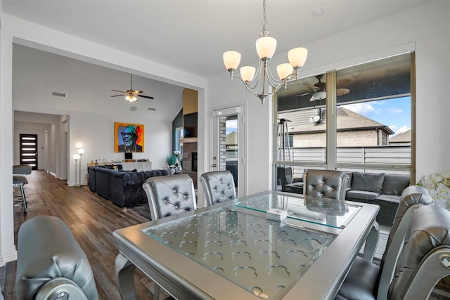 dining space featuring vaulted ceiling, wood finished floors, and ceiling fan with notable chandelier