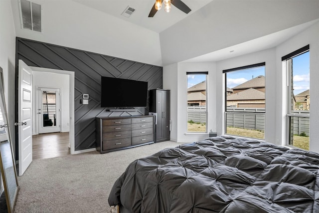 bedroom featuring visible vents, ceiling fan, light carpet, and a high ceiling