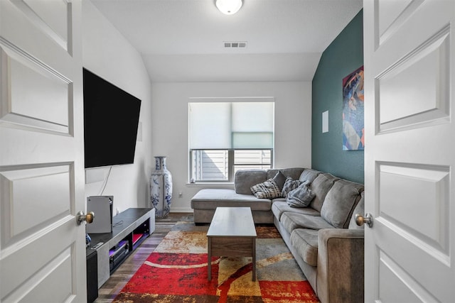 living room with lofted ceiling, wood finished floors, visible vents, and baseboards