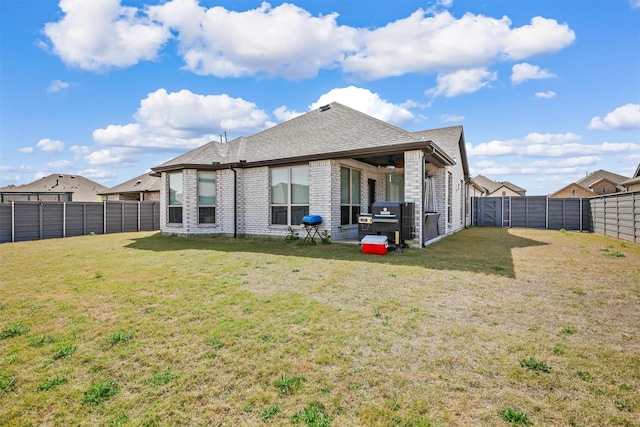 back of property with brick siding, a fenced backyard, roof with shingles, and a yard