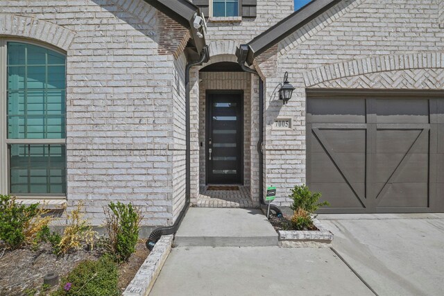 property entrance featuring brick siding and an attached garage