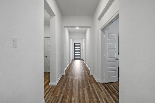 corridor with dark wood-style floors and baseboards