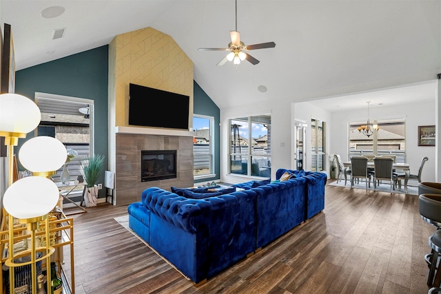 living area featuring high vaulted ceiling, ceiling fan with notable chandelier, wood finished floors, visible vents, and a tiled fireplace