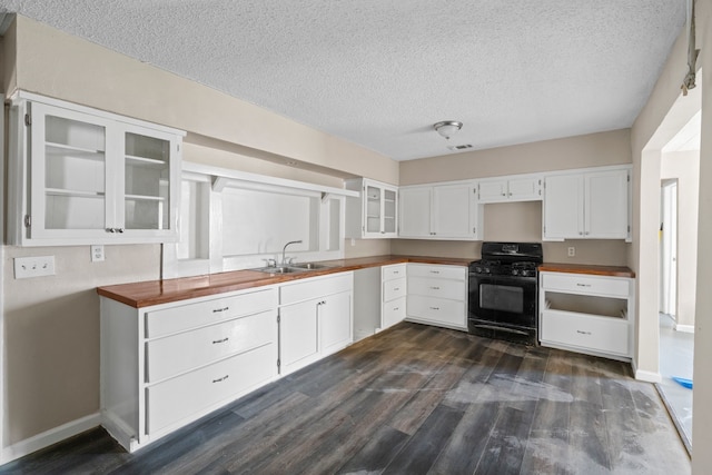 kitchen with dark wood-style flooring, visible vents, black range with gas stovetop, glass insert cabinets, and a sink