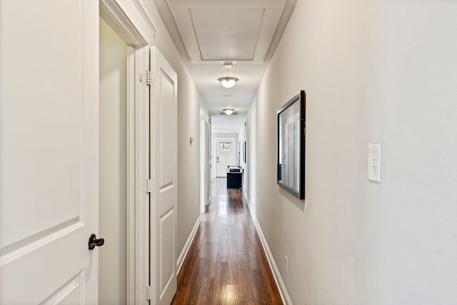 hallway with attic access, baseboards, and dark wood-style flooring