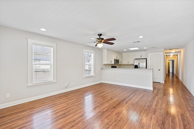 unfurnished living room featuring recessed lighting, wood finished floors, visible vents, and baseboards