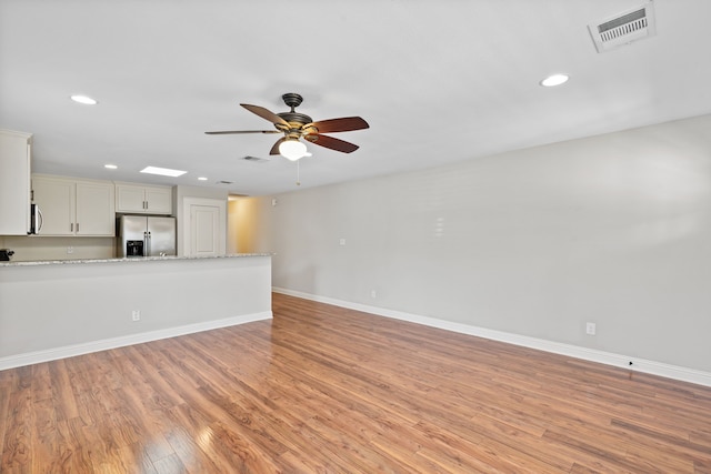 unfurnished living room with baseboards, visible vents, and light wood finished floors