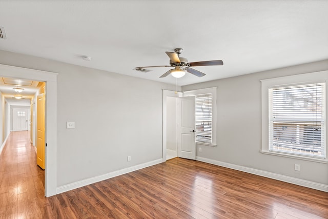 unfurnished bedroom with attic access, multiple windows, wood finished floors, and visible vents