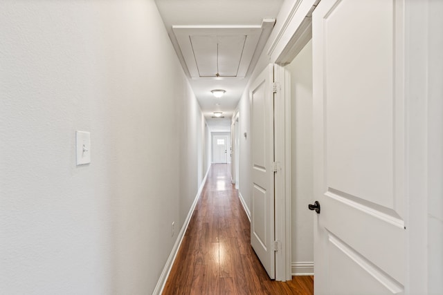 hall featuring attic access, baseboards, and dark wood-style flooring