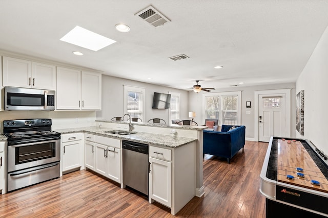 kitchen featuring visible vents, white cabinetry, a peninsula, and stainless steel appliances