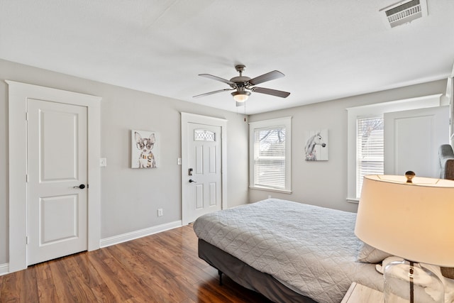 bedroom with multiple windows, wood finished floors, visible vents, and baseboards