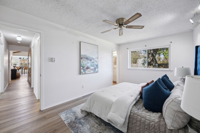 bedroom featuring ensuite bathroom, ceiling fan, a textured ceiling, wood finished floors, and baseboards