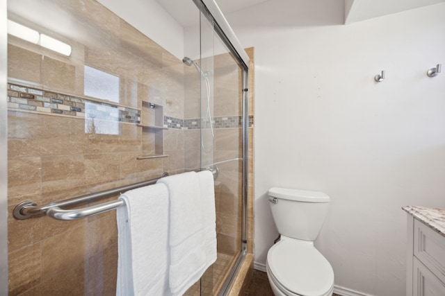 bathroom with toilet, a shower stall, and vanity