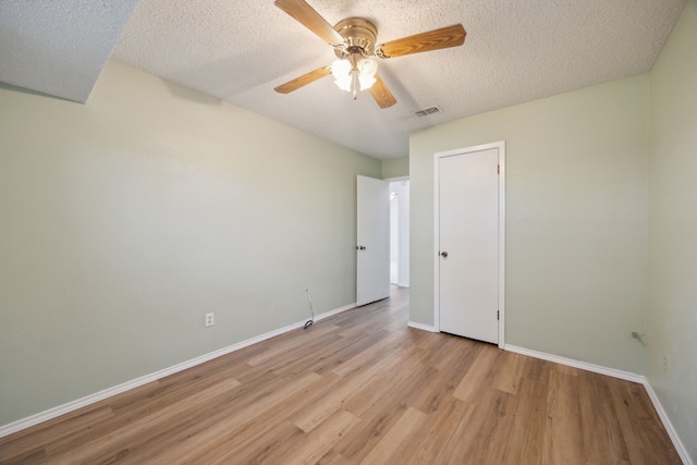 interior space featuring a textured ceiling, ceiling fan, wood finished floors, visible vents, and baseboards