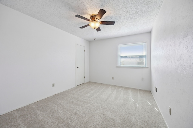 unfurnished room with a textured ceiling, carpet flooring, and a ceiling fan