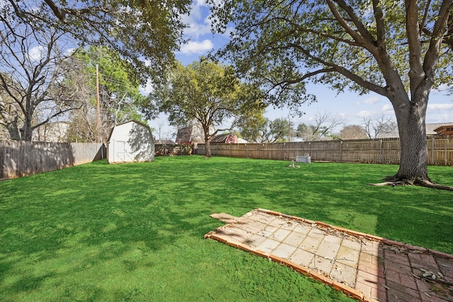 view of yard with a shed, a fenced backyard, and an outbuilding