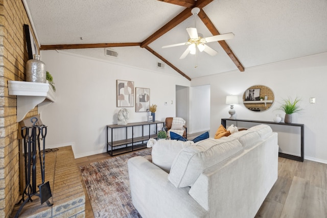 living area with visible vents, lofted ceiling with beams, a textured ceiling, and wood finished floors