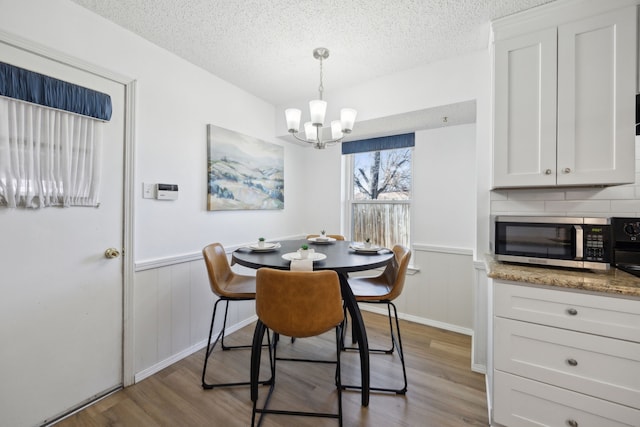 dining area featuring a textured ceiling, wainscoting, and wood finished floors