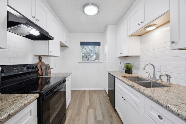 kitchen with white cabinetry, a sink, under cabinet range hood, and black appliances