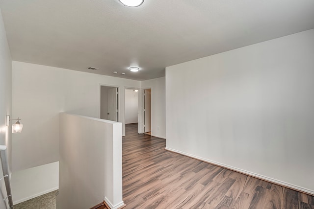 spare room featuring visible vents, baseboards, and wood finished floors