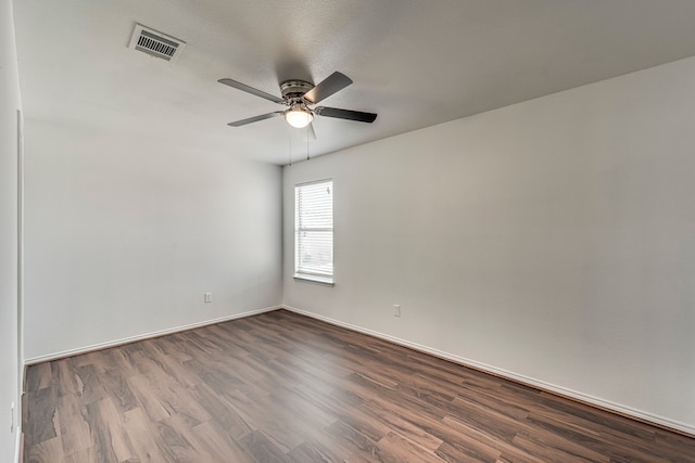 spare room with visible vents, baseboards, a ceiling fan, and dark wood-style flooring