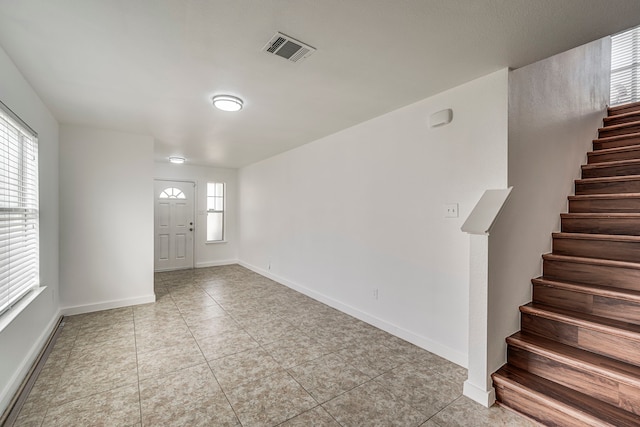 tiled foyer with visible vents, plenty of natural light, stairway, and baseboards