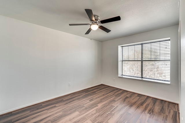 empty room featuring baseboards, a textured ceiling, dark wood-type flooring, and a ceiling fan