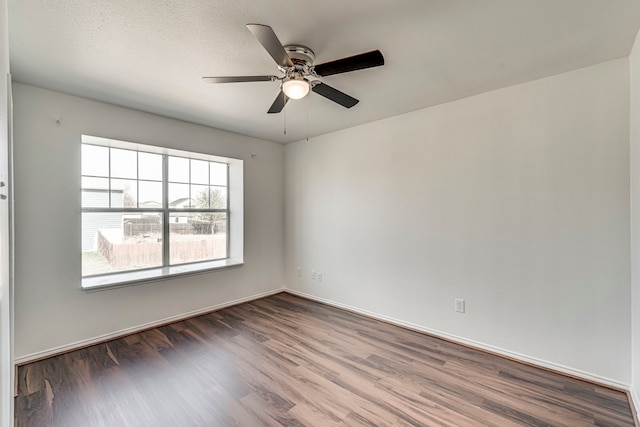 empty room featuring ceiling fan, baseboards, and wood finished floors